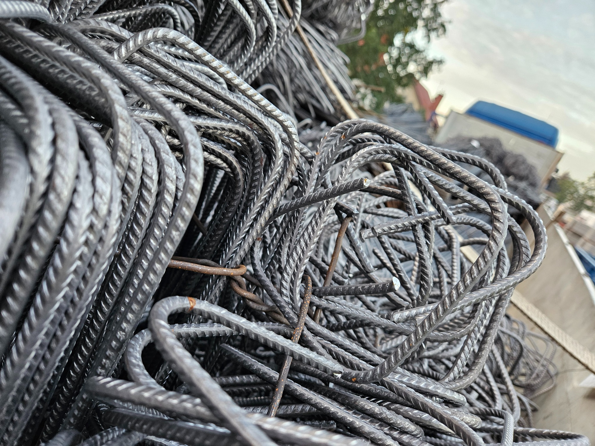 Stalowe pręty zbrojeniowe, uformowane w kwadratowe kształty, ułożone chaotycznie w skrzyni transportowej. Widoczne ślady rdzy na niektórych elementach.