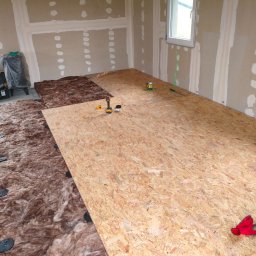 Maciej Arent - Poddasza i wykończenia - Montaż podłogi: wełna mineralna z czarnymi podkładkami i płyta OSB, narzędzia i laser krzyżowy. Ściany przygotowane do wykończenia.