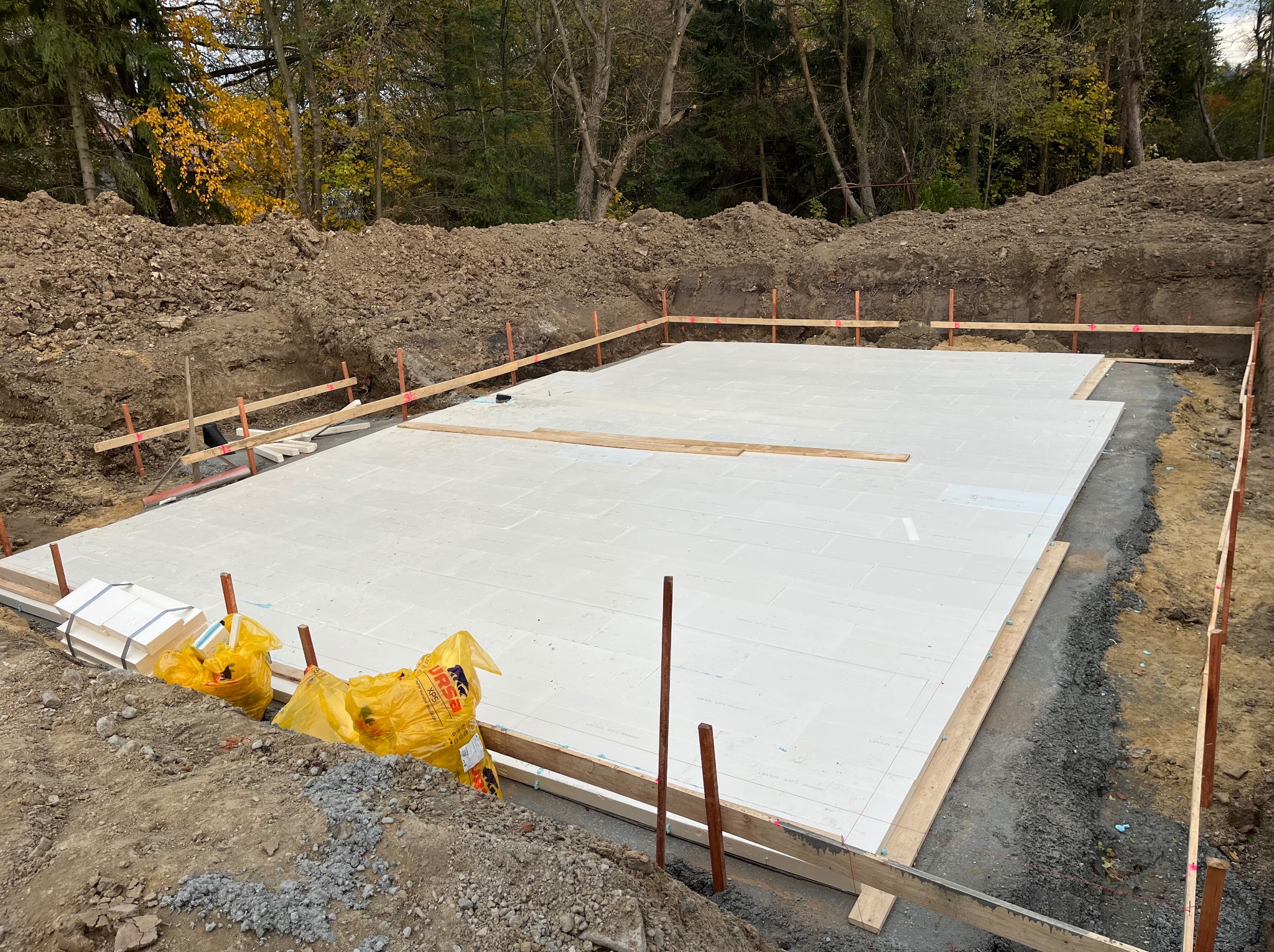 Przygotowany teren pod fundamenty z izolacją termiczną w Nowym Sączu. Widoczne drewniane szalunki i materiały izolacyjne. Wykop pod budowę domu.