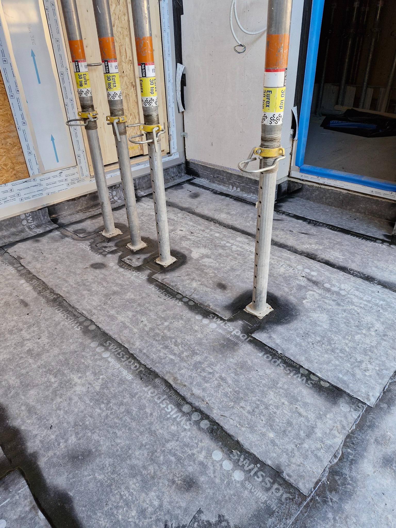 Płyty izolacyjne Swissopor na podłożu, wsparte metalowymi stemplami budowlanymi Eurex 30 top, przygotowane do dalszych prac wykończeniowych wewnątrz budynku.