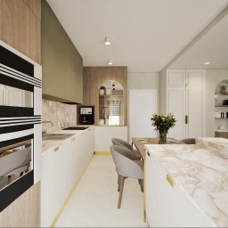 Inside House - Ewa Antczak - Elegancka kuchnia z marmurowymi blatami, złotymi akcentami i nowoczesnym sprzętem. Widoczny stół z krzesłami i dekoracyjna półka w kształcie łuku.