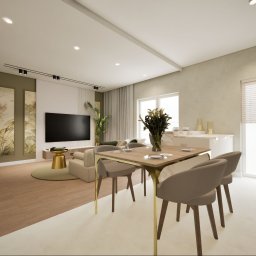 Inside House - Ewa Antczak - Wnętrze salonu z jadalnią w neutralnych barwach. Stół z krzesłami na pierwszym planie, w tle sofa, telewizor i dekoracje. Całość w nowoczesnym stylu z akcentami roślinnymi.