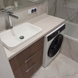 Łukasz Machnio - Nowoczesna łazienka z umywalką nablatową, szafką z drewnopodobnym frontem i pralką pod blatem. Marmurowe płytki na ścianach i podłodze.