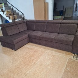 Tapicerstwo Meblowe - Brązowy narożnik tapicerowany z funkcją spania i pojemnikiem na pościel, widoczny w warsztacie na tle schodów i elementów konstrukcyjnych.