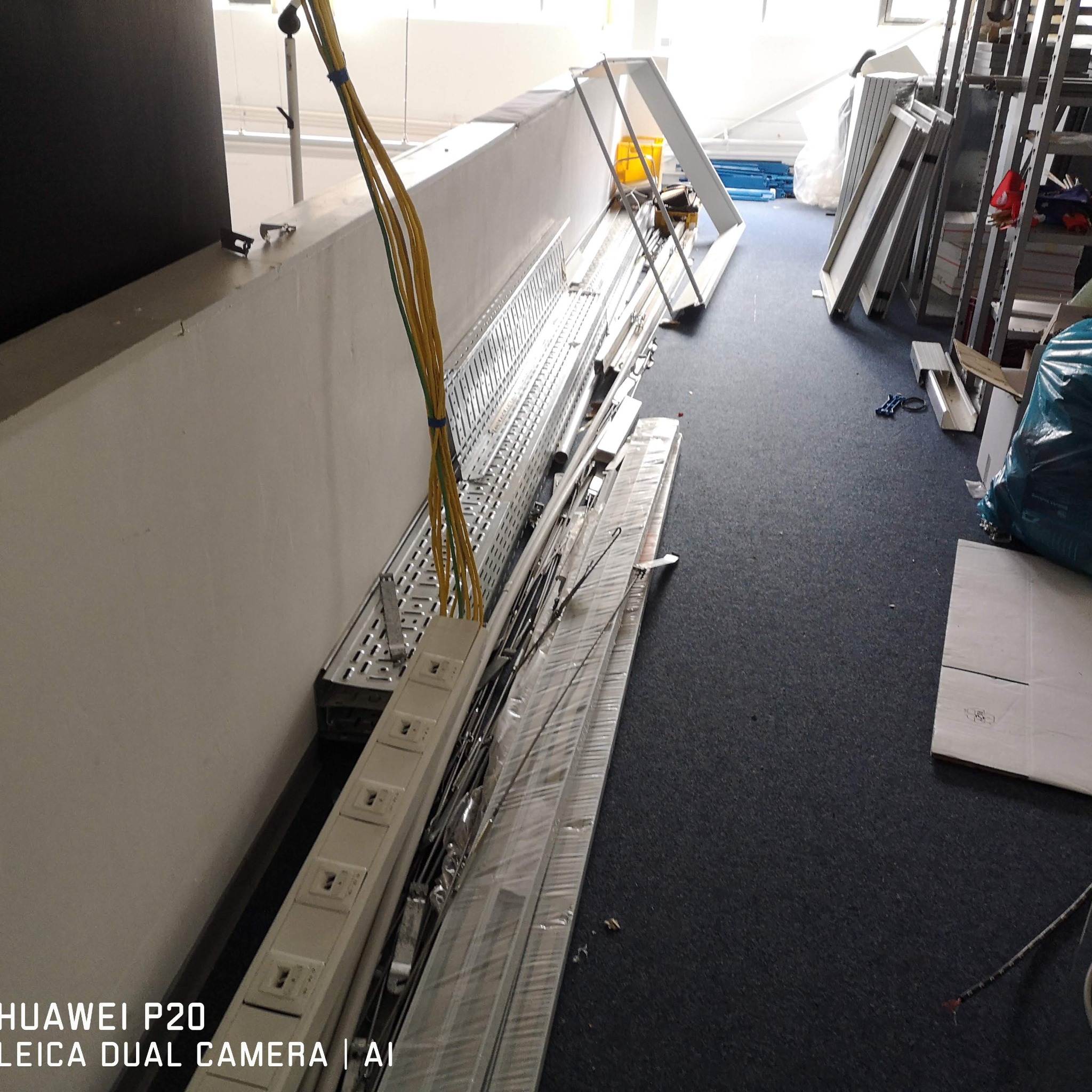 Przygotowane koryta kablowe, przewody i listwy LED z gniazdami, czekające na montaż przy ścianie. Elementy instalacji elektrycznej w pomieszczeniu.