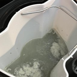 Fabryka Świeżości - Brudna woda po czyszczeniu w zbiorniku maszyny do prania tapicerki, widoczne drobinki i piana. Zbiornik w kolorze białym, maszyna czarna.
