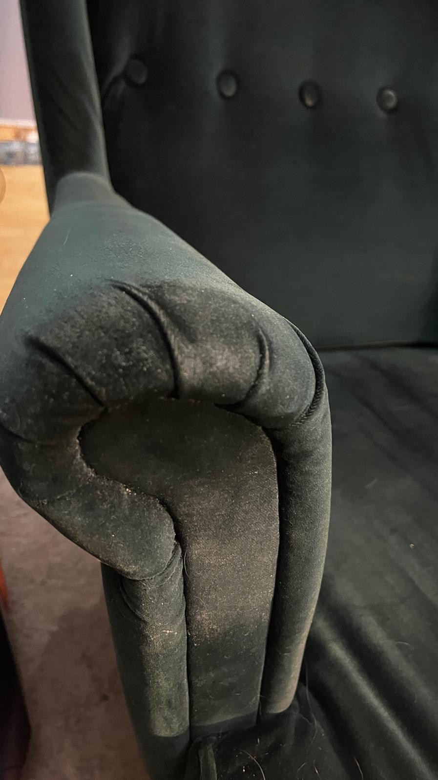 Brudny, zielony, welurowy podłokietnik fotela z widocznymi plamami i kurzem, wymagający czyszczenia. Detal tapicerki przed zabiegiem odświeżającym.