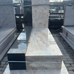 MAT GRAN Nagrobki - Dwukolorowy, poziomy pomnik z jasnego i czarnego kamienia, z widocznym odbiciem nieba na polerowanej powierzchni. Widoczne inne elementy kamienne w tle.