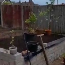 Bartosz Bojanowski - Budowa podwyższonej rabaty kwiatowej z cegły w ogrodzie w Gdańsku. Widoczne narzędzia ogrodnicze i donice z roślinami. Etap prac w toku, świeżo nasypana ziemia.