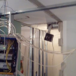 Dar-bud usługi ogólno budowlane - Instalacja elektryczna w trakcie montażu, widoczne przewody, puszki i metalowa konstrukcja ścianki działowej. Prace wykończeniowe w surowym wnętrzu.