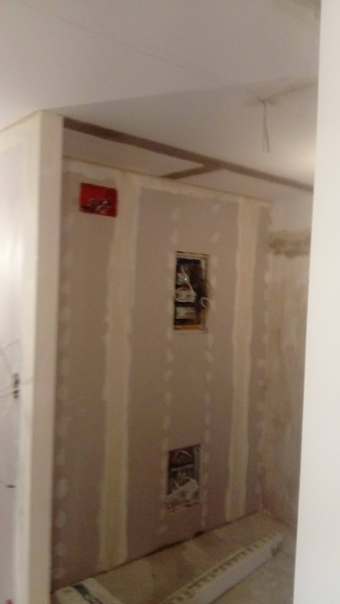 Ściana z płyt karton-gips z widocznymi puszkami elektrycznymi przed szpachlowaniem. Widoczne łączenia płyt. Prace wykończeniowe w trakcie realizacji.