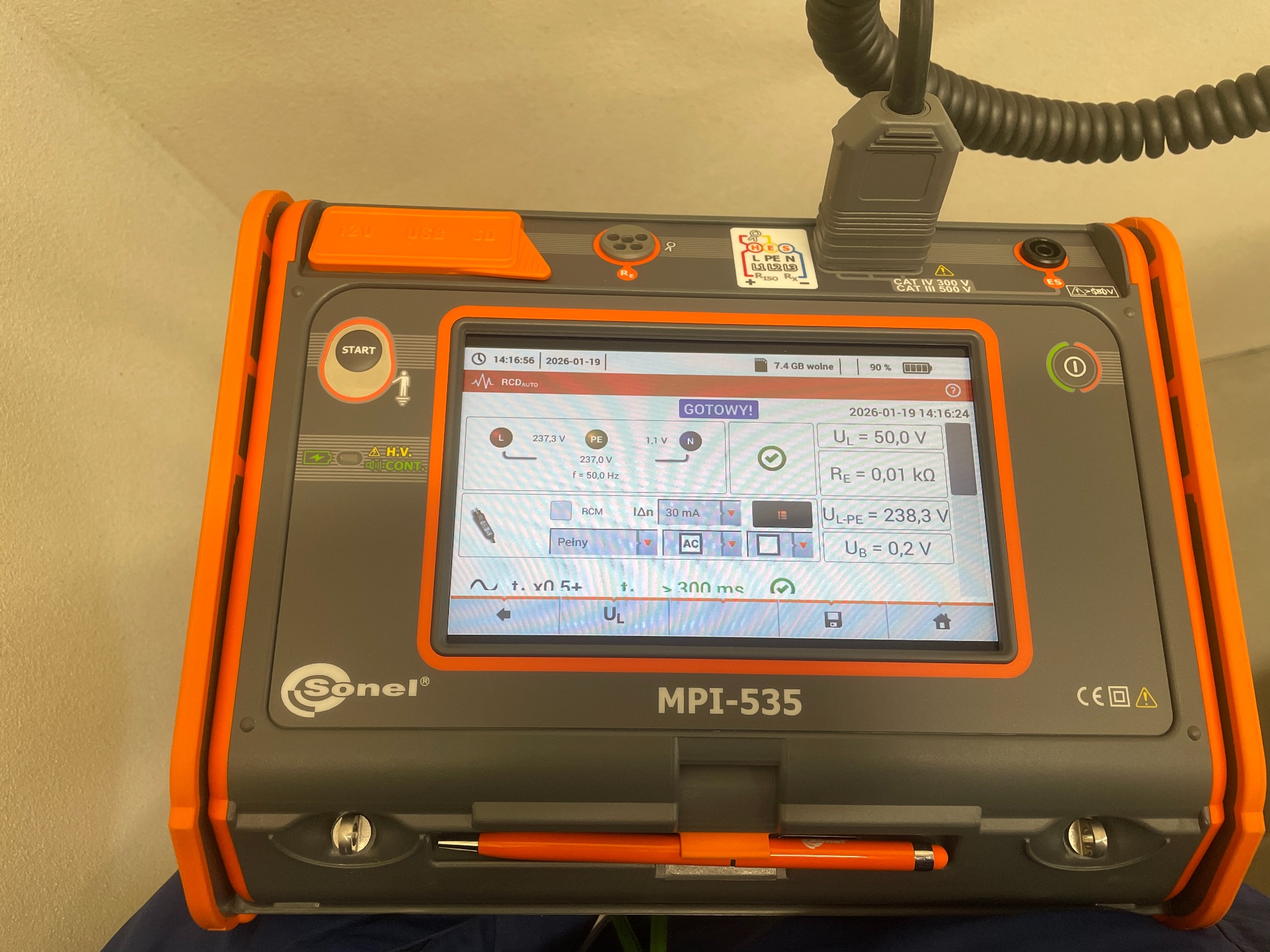 Miernik Sonel MPI-535 z ekranem wyświetlającym wyniki pomiarów elektrycznych, ustawiony na płaskiej powierzchni. Widoczne parametry napięcia, rezystancji i częstotliwości.