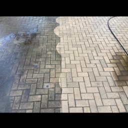 MK Błysk - Kostka brukowa częściowo umyta, ukazująca różnicę w wyglądzie przed i po czyszczeniu. Widoczna linia podziału i fragment węża ciśnieniowego.