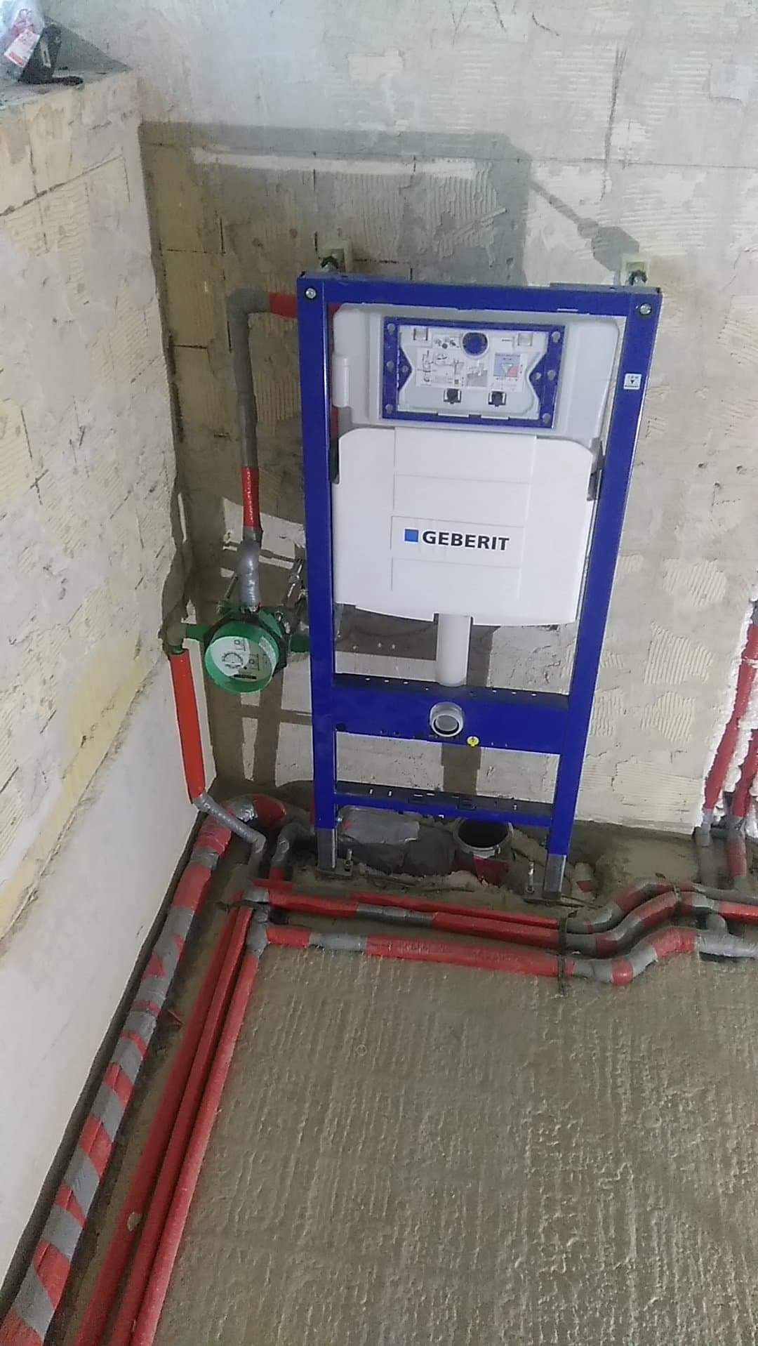 Stelaż podtynkowy Geberit zamontowany w surowej łazience, widoczne rury instalacji wodnej i kanalizacyjnej. Etap prac instalacyjnych przed wykończeniem.