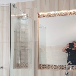 EXPERT Ryszard Studniarz - Wykończona łazienka z kabiną prysznicową typu walk-in, lustrem z dekoracyjnym oświetleniem i wnęką z mozaiką. Osoba robiąca zdjęcie widoczna w lustrze.