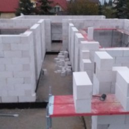 Firma Budowlana Piotr Milewski - Wznoszenie ścian działowych z białych bloczków betonu komórkowego. Widoczne fragmenty rusztowania i narzędzia murarskie. Budowa domu w trakcie realizacji.