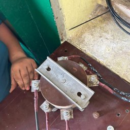 Maciej Radziwiłł - White Energy - Podłączenie przewodów do transformatora z użyciem metalowej listwy. Widoczne śruby, nakrętki i izolacja przewodów. Praca w toku, widoczna dłoń.