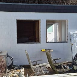 BMHS - Biały budynek z dwoma otworami okiennymi, jeden bez okna, drugi z częściowo zamontowanym oknem. Widoczne narzędzia i materiały budowlane. Prace w toku.