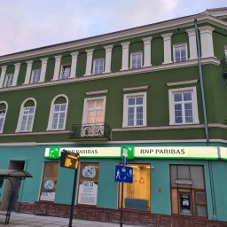 PAMAR PLUS SPÓŁKA Z OGRANICZONĄ ODPOWIEDZIALNOŚCIĄ - Odnowiona elewacja dwukondygnacyjnego budynku banku BNP Paribas w odcieniach zieleni i turkusu, z białymi kolumnami i balkonami, widok z poziomu ulicy.