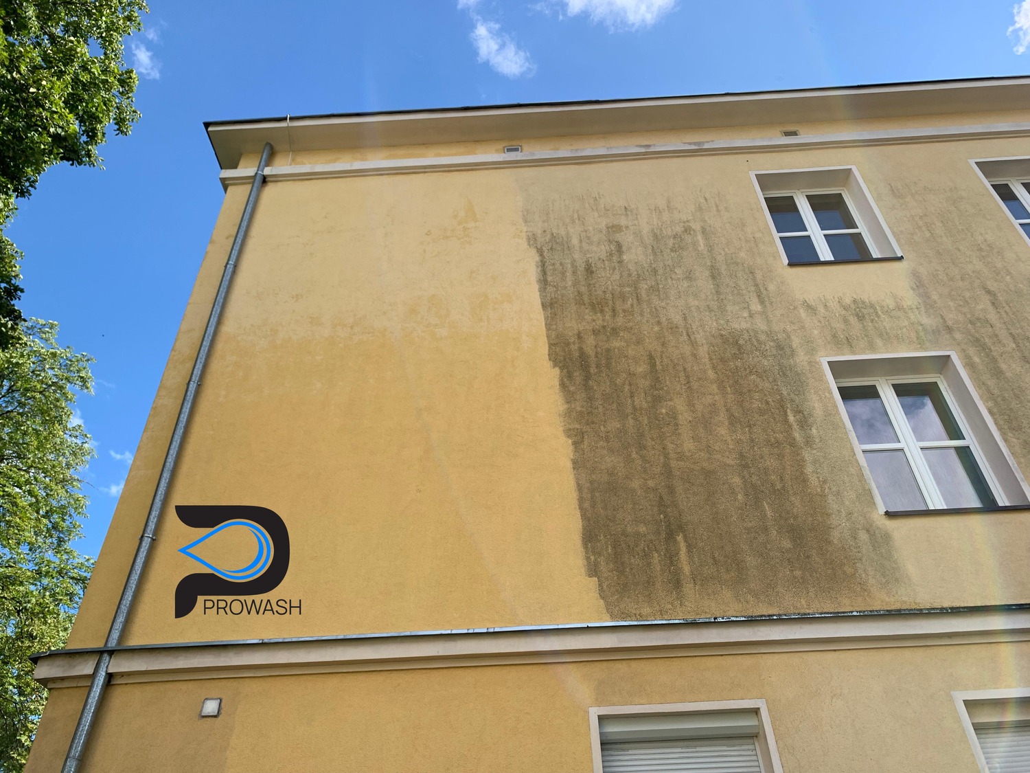 Żółta elewacja budynku z widoczną różnicą po czyszczeniu: lewa strona jaśniejsza, prawa pokryta ciemnym nalotem. Logo firmy w lewym dolnym rogu.