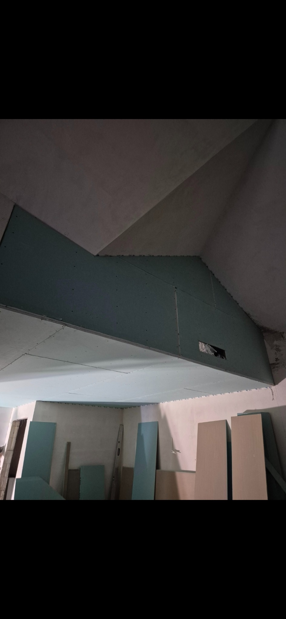 Montaż płyt karton-gips na skośnym suficie poddasza, widoczne płyty i konstrukcja, surowy stan wykończenia, przygotowanie do dalszych prac.