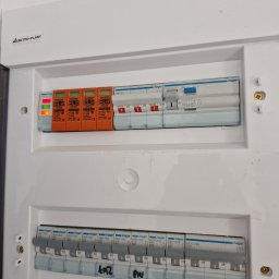 Daniel Szczepański - Rozdzielnica elektryczna z zabezpieczeniami przepięciowymi ELS i wyłącznikami Hager. Widoczne oznaczenia i parametry urządzeń. Tabliczka Elektro-Plast.