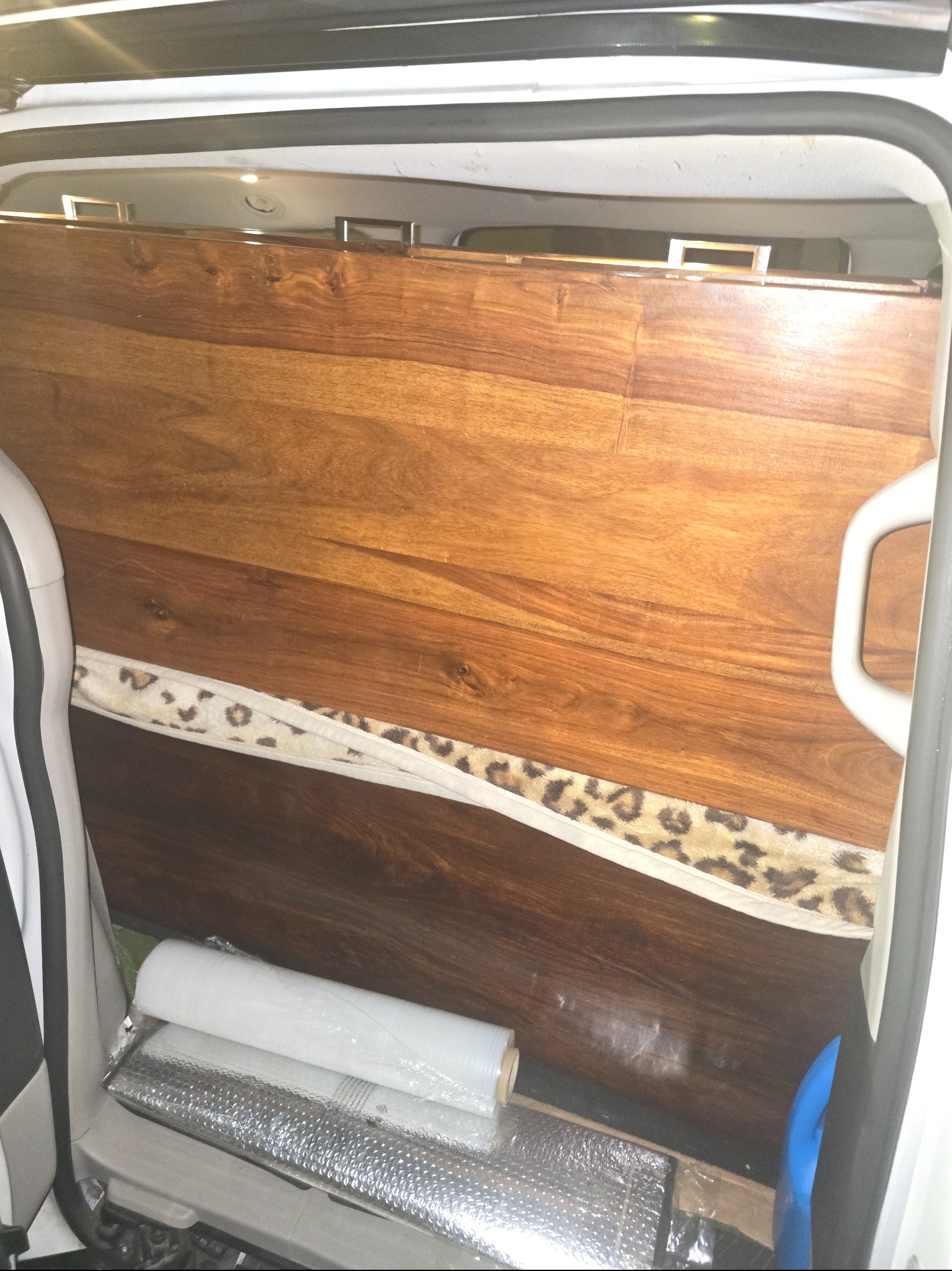 Wnętrze busa z zabezpieczonym ładunkiem: drewniana płyta z futrzanym obiciem, folia bąbelkowa i stretch. Gotowość do transportu.