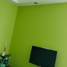 USŁUGI U RAFAŁA Rafał Zieliński - Jasnozielony pokój z telewizorem na ścianie i choinką w rogu. Sufit z fakturą, szafka pod telewizorem z dekoracjami.