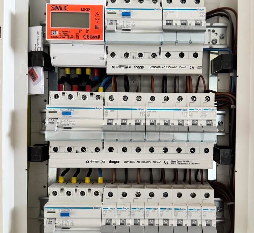 Rozdzielnica elektryczna z zabezpieczeniami Hager, widoczne przewody z oznaczeniami kolorystycznymi i licznik energii Simlic LS-3F. Estetyczne i uporządkowane ułożenie.