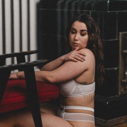 Bartłomiej Czernecki - Kobieta w bieliźnie pozuje siedząc na podłodze obok krzesła. Uwagę przykuwa tatuaż na żebrach i pierścionek na palcu. Stonowana kolorystyka i miękkie światło.