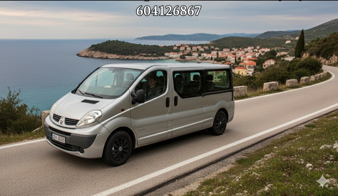 Srebrny bus Renault Trafic na krętej drodze z widokiem na morze i miasteczko w tle. Czarny felgi. Krajobraz Chorwacji. Transport.
