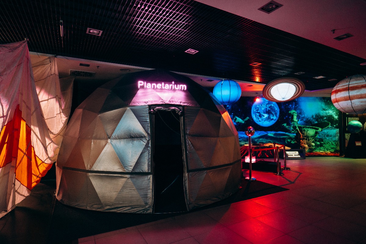 Planetarium w Warszawie z neonowym napisem, widoczne dekoracje kosmiczne i oświetlenie sceniczne, tworzące unikalną atmosferę eventową.