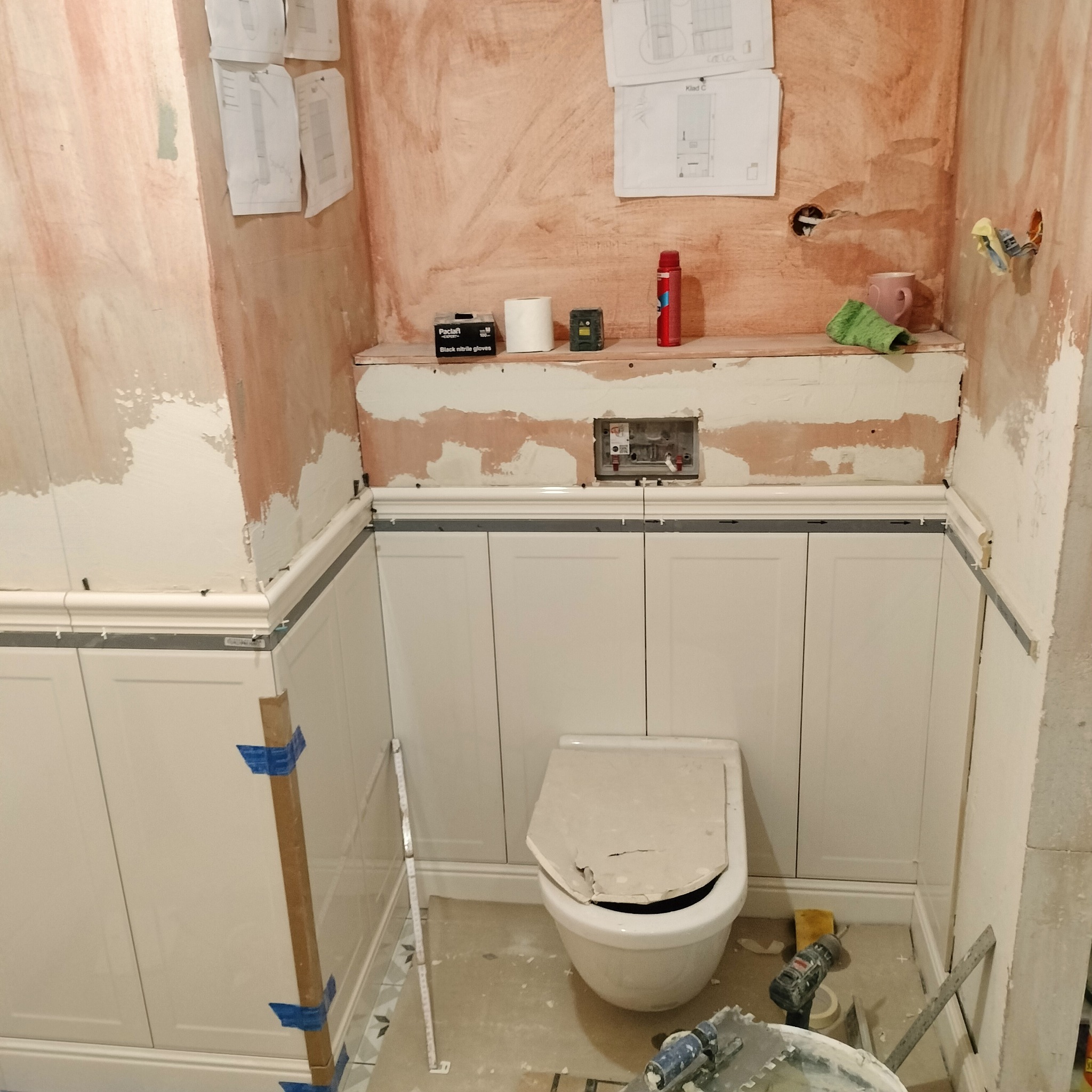 Remont łazienki w Gniezno: montaż paneli ściennych i zabudowy WC. Widoczne narzędzia i materiały budowlane, ściany przygotowane do dalszych prac wykończeniowych.