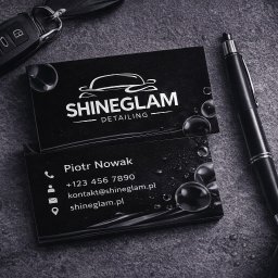 Shinedesing Klaudia Pikulik - Stylowe, czarno-białe wizytówki Shineglam Detailing z logo auta, leżące na szarym tle z kroplami wody, obok kluczyka samochodowego, długopisu i butelki z atomizerem.