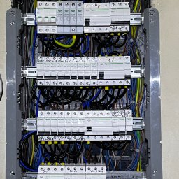 MultiSystem - Rozdzielnica elektryczna z zainstalowanymi bezpiecznikami i okablowaniem. Widoczne opisy obwodów na bezpiecznikach. Estetyczne ułożenie przewodów wewnątrz skrzynki.