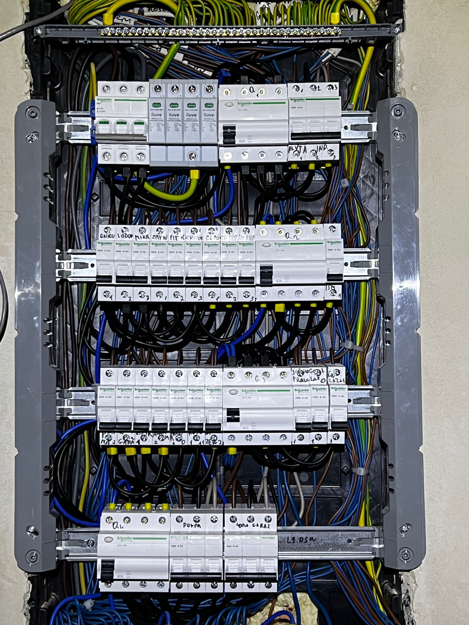 Rozdzielnica elektryczna z zainstalowanymi bezpiecznikami i okablowaniem. Widoczne opisy obwodów na bezpiecznikach. Estetyczne ułożenie przewodów wewnątrz skrzynki.