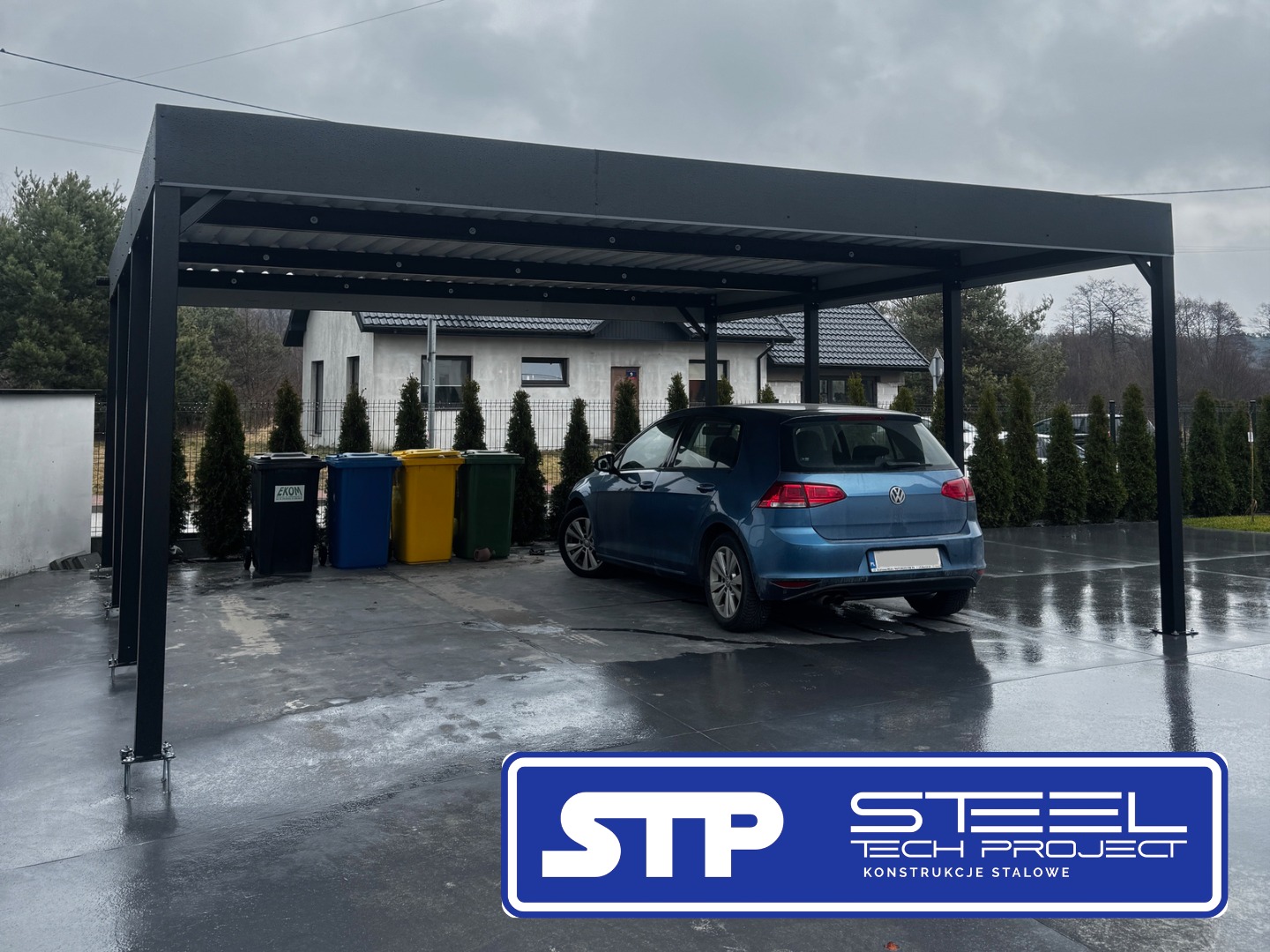 Nowoczesna, grafitowa konstrukcja zadaszenia nad miejscem parkingowym, z zaparkowanym niebieskim samochodem i zestawem kolorowych pojemników na odpady w tle.