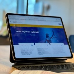 CONTA NOVA SPÓŁKA Z OGRANICZONĄ ODPOWIEDZIALNOŚCIĄ - Tablet z otwartą stroną Portalu Rejestrów Sądowych, na biurku w Grodzisku Mazowieckim. Widoczne dokumenty w tle. Usługi online dla firm i obywateli.