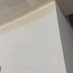 Przemysław Łabiak - Wnętrze po szpachlowaniu: gładka, biała ściana z widoczną taśmą wzmacniającą na styku ze sufitem. Przygotowanie do malowania.