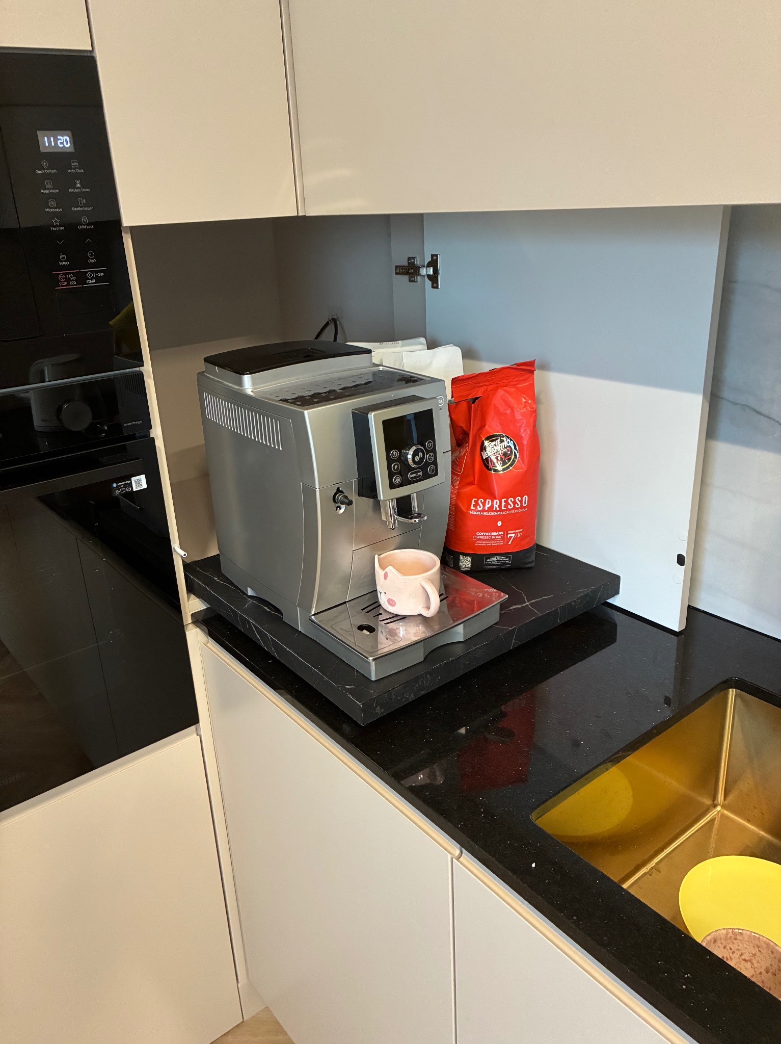 Kompaktowa kuchnia w Bydgoszczy: zabudowa z szarymi frontami, czarnym blatem i wbudowanym ekspresem do kawy. Minimalistyczny design, nowoczesne AGD.