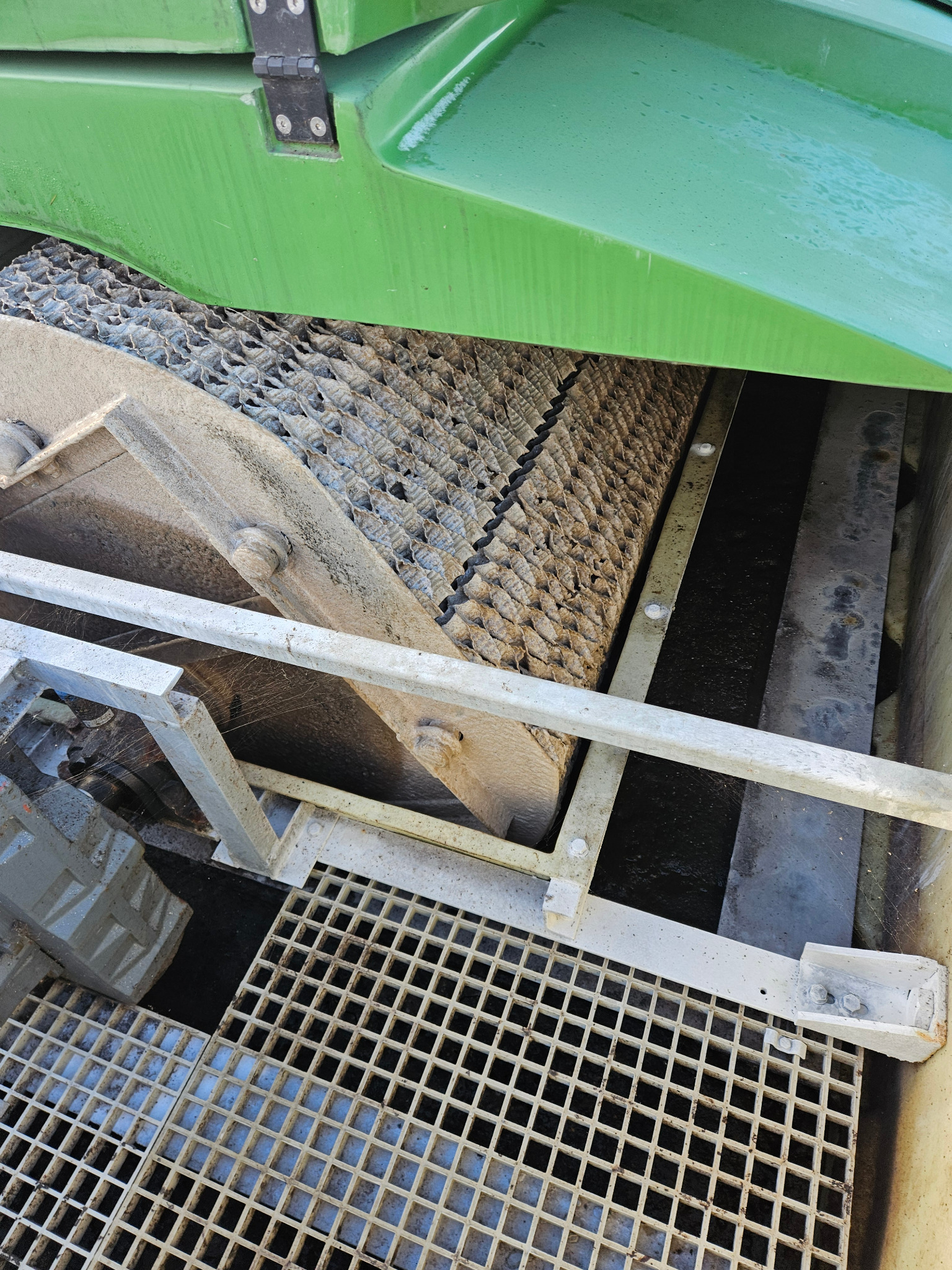 Wnętrze oczyszczalni ścieków z widocznym filtrem kasetowym i kratą pomostową. Elementy konstrukcyjne w odcieniach szarości i zieleni. Widoczne ślady eksploatacji.