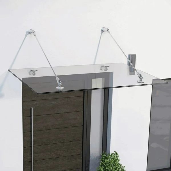 Szklany daszek nad wejściem z chromowanymi mocowaniami, nowoczesny design. Ciemne drzwi wejściowe z długim, pionowym uchwytem. Minimalistyczny styl.