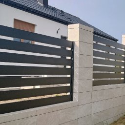 Usługi Ogólnobudowlane Stal-Pro - Nowoczesne ogrodzenie panelowe z poziomymi, czarnymi przęsłami i jasnymi, kamiennymi słupkami. Widok na fragment domu w tle. Minimalistyczny design.