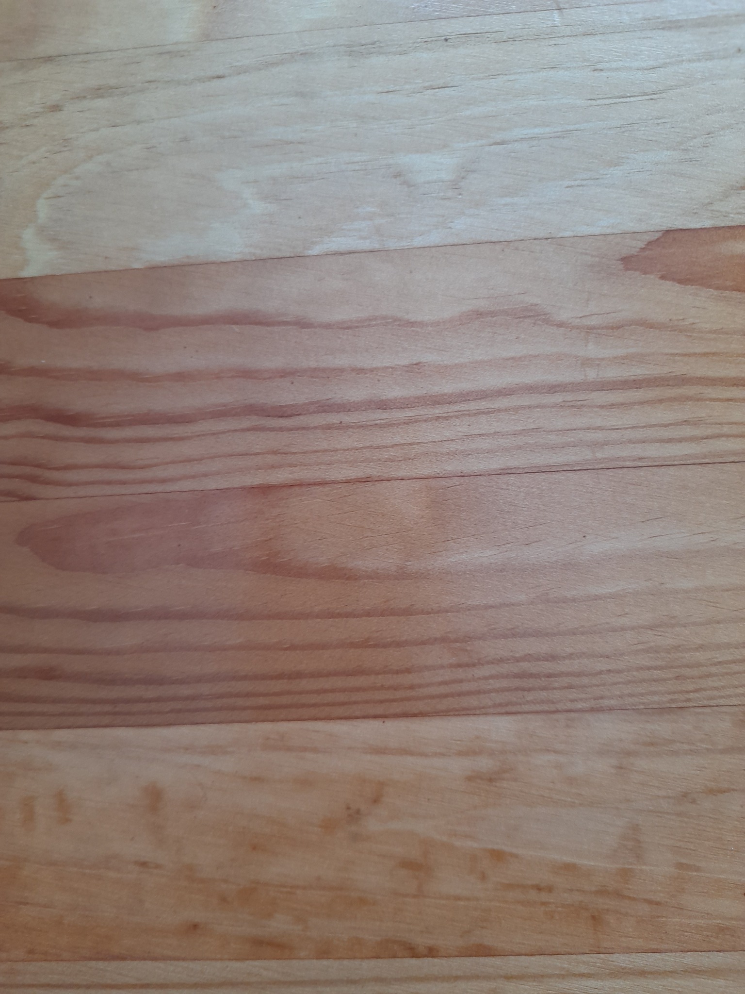 Jasne, drewniane deski podłogowe ułożone poziomo, z widocznym usłojeniem i naturalnymi przebarwieniami. Powierzchnia czysta, bez śladów użytkowania.