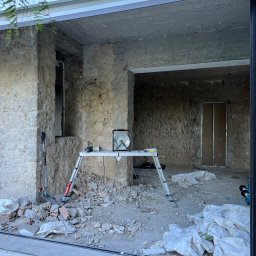 Son-Car - Wnętrze w trakcie remontu: surowe ściany z kamienia, gruz na podłodze, drabina, lampa na podeście. Widoczne ślady prac rozbiórkowych i przygotowania do dalszych etapów.