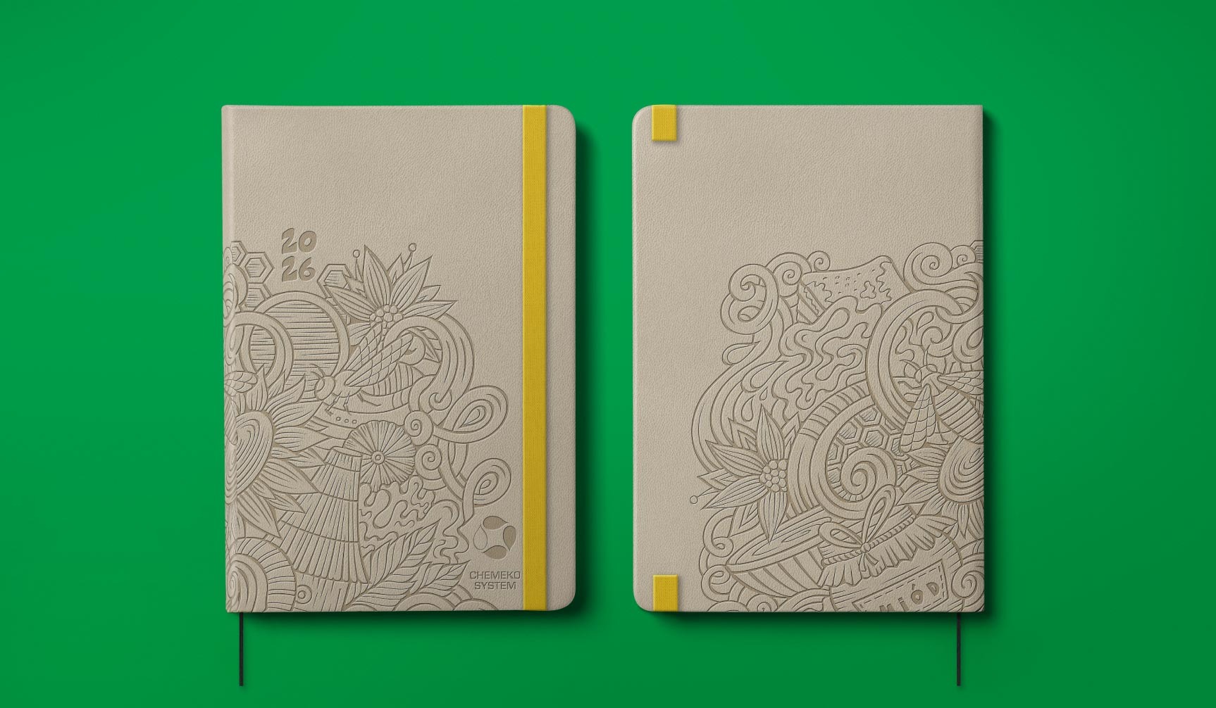 Dwa beżowe notesy z tłoczonym wzorem roślinnym i logo firmy, połączone żółtą gumką na zielonym tle. Jeden z datą '2026'.