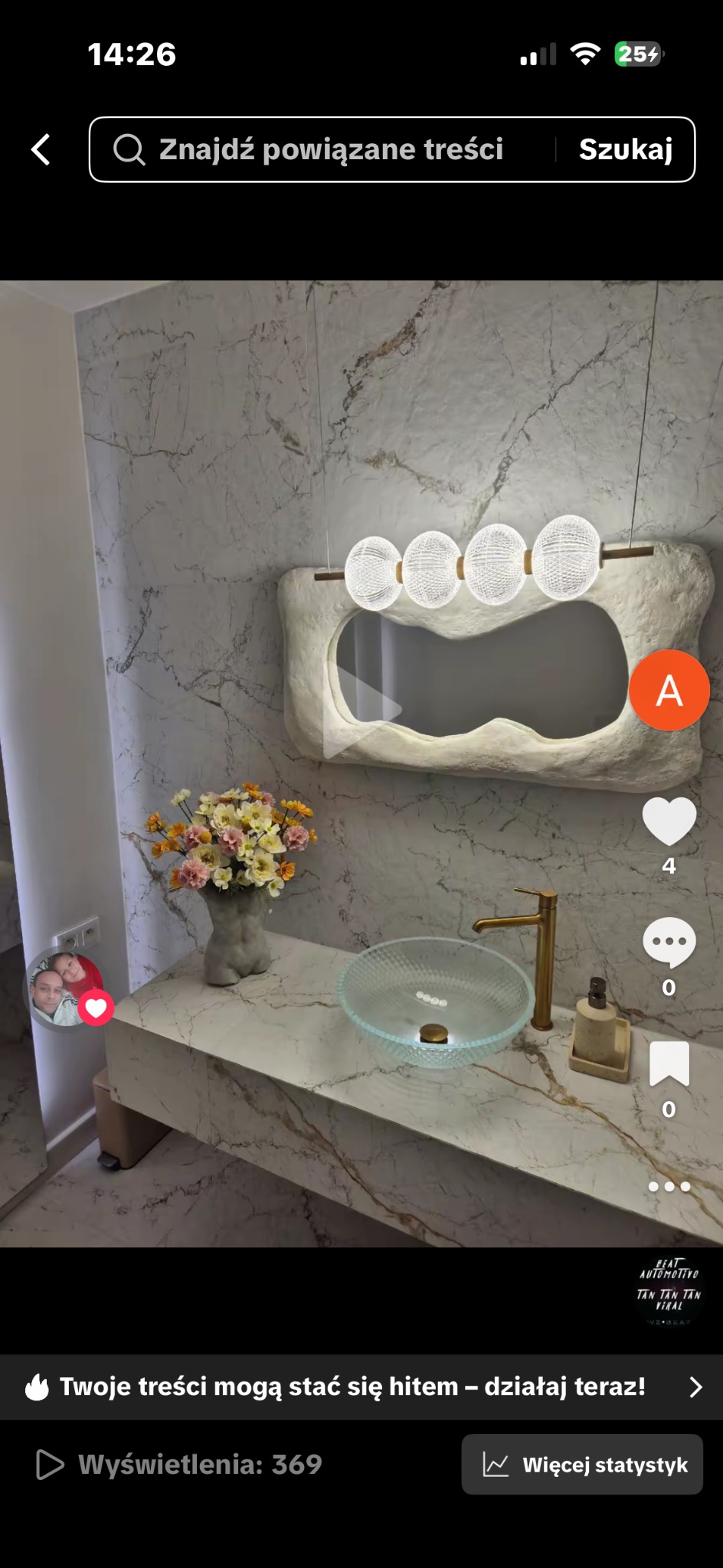 Nowoczesna łazienka z marmurowymi ścianami, szklaną umywalką i designerskim lustrem z oświetleniem. Na blacie wazon z kwiatami i złota bateria.