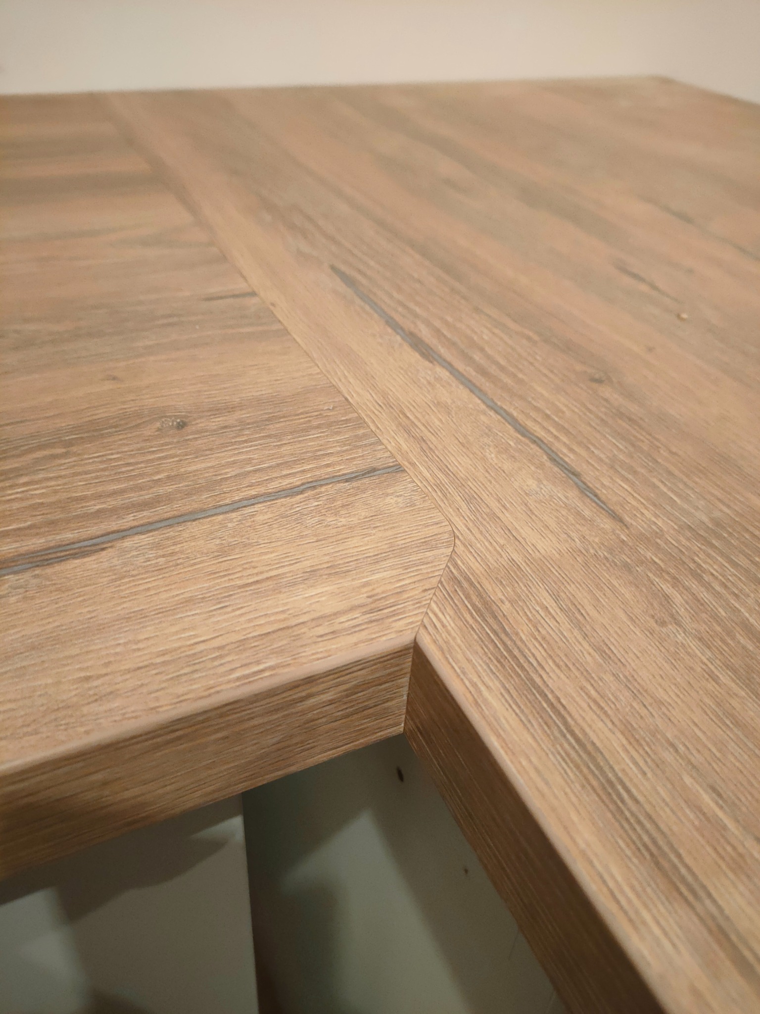 Połączenie dwóch blatów drewnianych pod kątem, tworzących narożnik. Widoczne usłojenie drewna i precyzyjne wykończenie krawędzi. Blat o ciepłej, naturalnej kolorystyce.