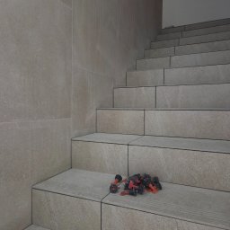 ArtBud - Wykończone schody z płytek w odcieniach beżu i szarości, z widocznymi elementami systemu poziomowania płytek na jednym ze stopni. Minimalistyczny design.