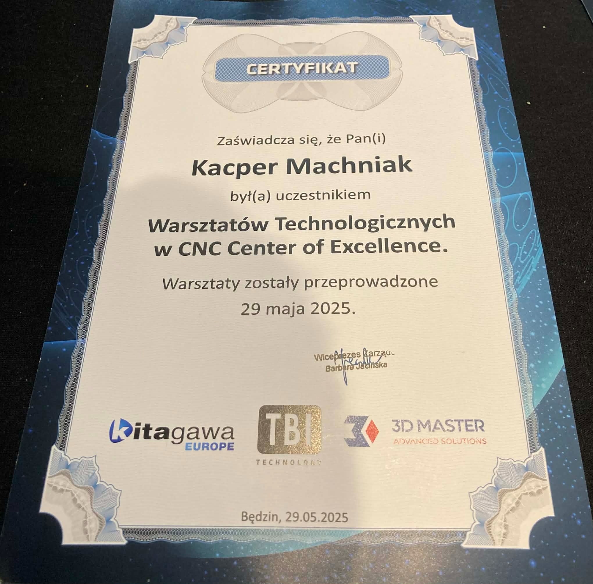 Certyfikat ukończenia warsztatów technologicznych CNC Center of Excellence dla Kacpra Machniaka, wydany 29 maja 2025 w Będzinie. Sygnatury Kitagawa, TBI Technology i 3D Master.